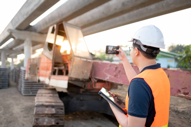 азиатский рабочий с помощью цифрового планшета на строительной площадке - digital tablet construction truck manual worker стоковые фото и изображения