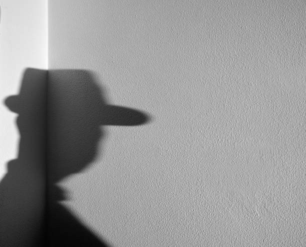 istock Shadow of a man with a hat on a white wall 1304084769