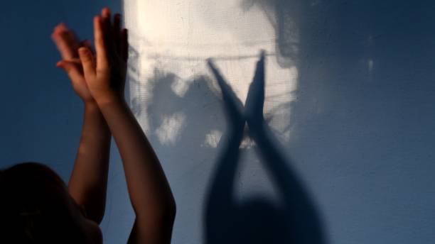 istock Defocus shadows of kid clapping hands on stucco wall surface with copy space. Halloween concept 1304085091