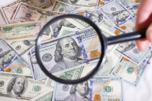 istock Magnifying glass on the background of bundle dollars - texture, background 1304086541