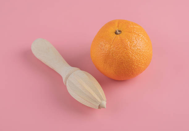 istock Orange and wooden reamer on pink background 1304095393
