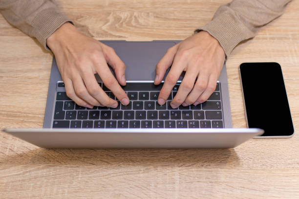istock hands on laptop keyboard with mobile phone on desk 1304095581