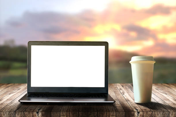 istock Laptop computer and white plastic takeaway coffee cup on old brown wooden table with rural nature view and mountain with nice sky background and sunrise in morning, Calm and relaxing, Work at home. 1304098196