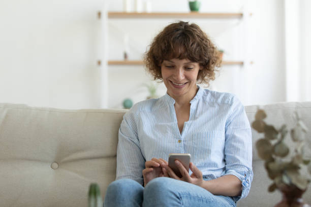 istock Smiling woman relax on sofa using cellphone 1304099368