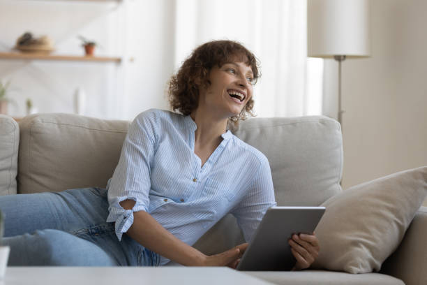 istock Happy woman rest on couch browsing tablet 1304099373