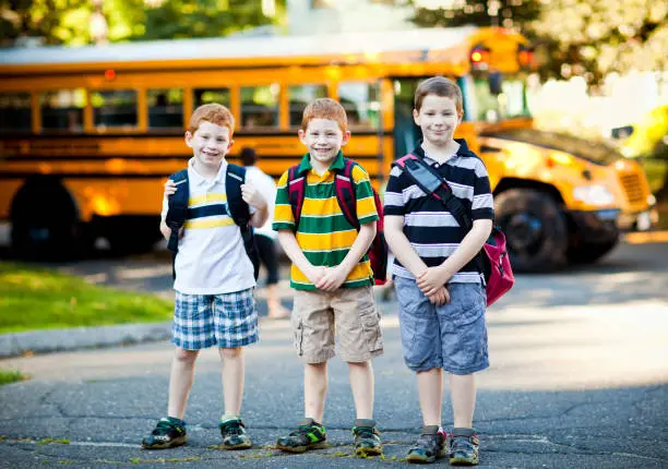 Three boys in front of a school bus