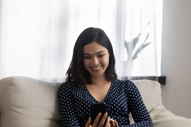 istock Smiling vietnamese asian woman using smartphone at home. 1304102538