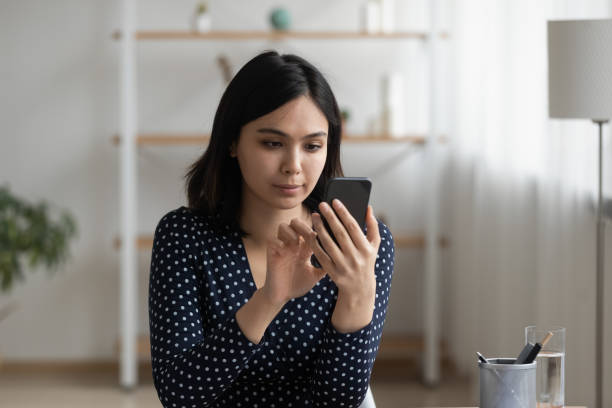 istock Focused millennial asian woman using mobile phone software applications. 1304102645