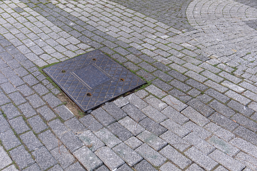 An old sewer manhole cover surrounded by an asphalt street