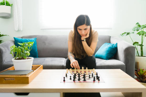 istock Latin woman sitting on the sofa and playing a board game 1304112913