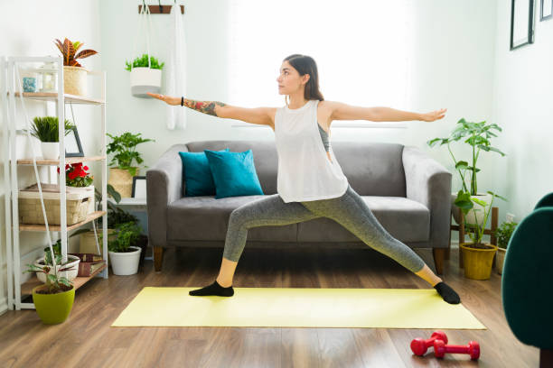 istock Hispanic woman practicing a warrior yoga pose at home 1304114846