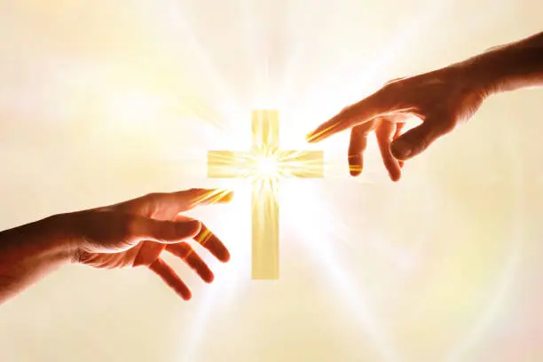 Hands wanting to touch a cross with flash of light. Concept of believing and following christ