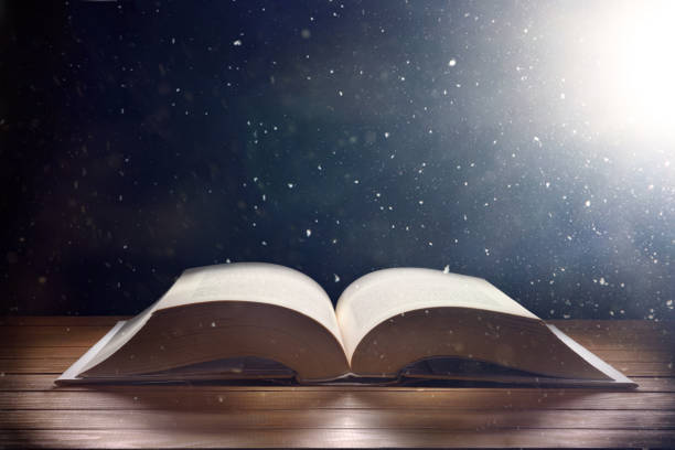 istock Mystical book on wooden table with light shine and dust 1304117135