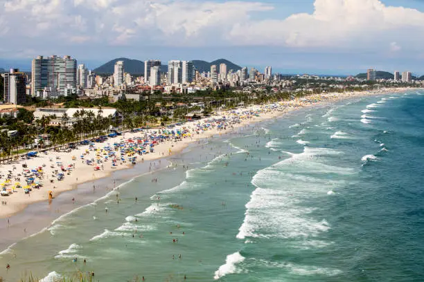 Aerial view of Enseada Beach at Guaruja SP Brazil. People on the beach, the sand, sea waves and the city on background. Place known as Praia da Enseada. Brazilian coastal city.