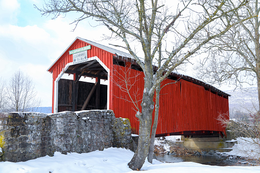 Horizontal image of the New Germantown covered bridge, in Perry County, PA, surrounded by snow and trees.