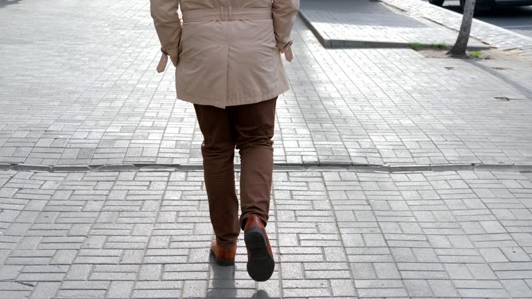A guy walks down the street with a long, confident stride. Close-up steps. Slow motion