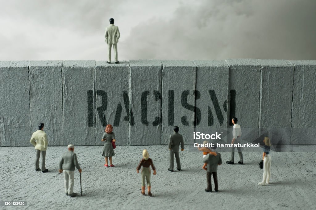 Wall 2 People figurines looking at the Racism warning on the wall. Uncertainty concept Racism Stock Photo