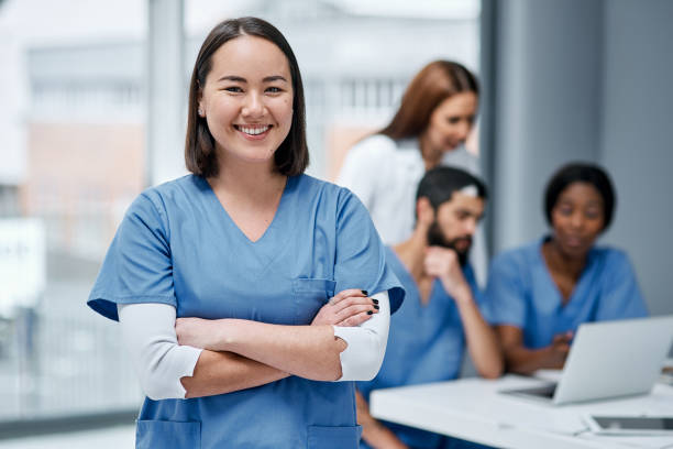 Always willing to go the extra mile for you Portrait of a doctor standing in a hospital with her colleagues in the background female nurse photos stock pictures, royalty-free photos & images