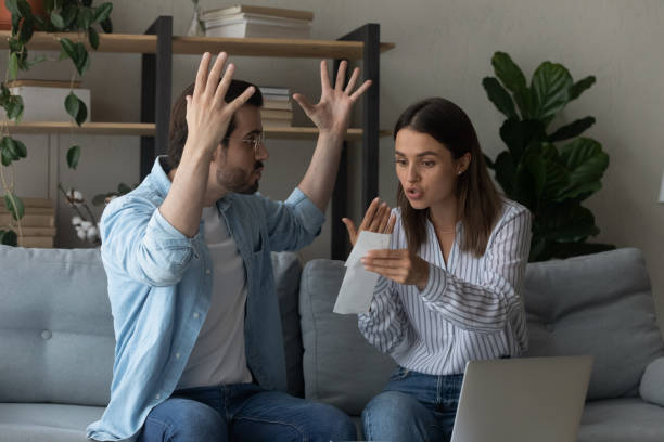 pareja emocional estresada discutiendo peleando al revisar papeles financieros - discusión fotografías e imágenes de stock