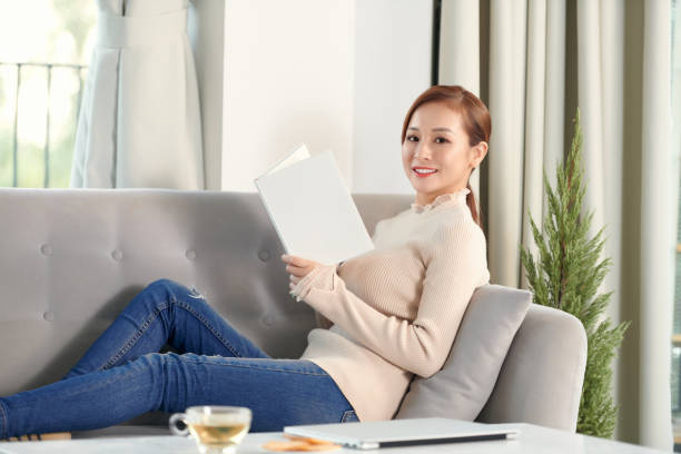 istock Young asian woman reading a book at home 1304134020