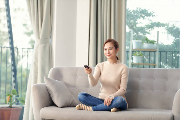 istock Women watching TV on the sofa at home with remote control 1304134268