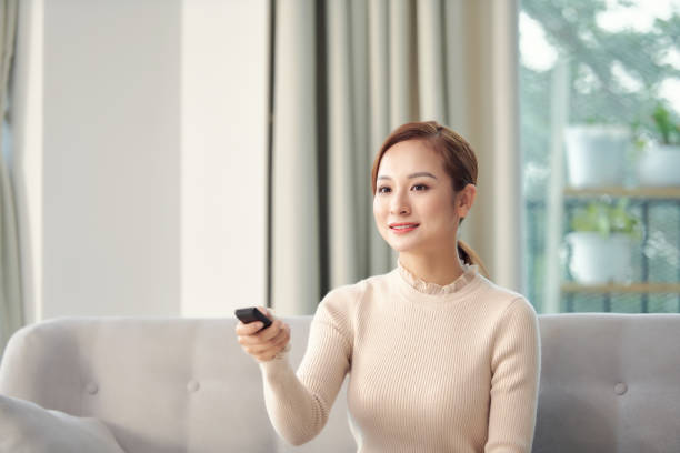 istock Happy young woman watching tv on sofa 1304134296