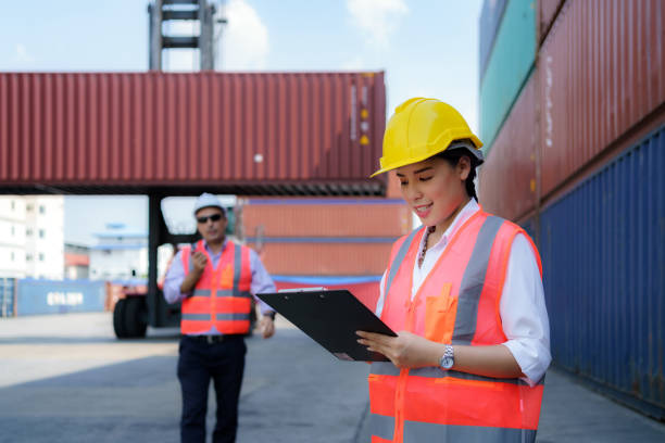 istock Asian worker woman is checking the container after the repair complete with foreman using walkie talkie to command crane lifting container in background. 1304135938