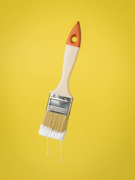 istock Paint brush with dripping white paint on a yellow background. 1304136117