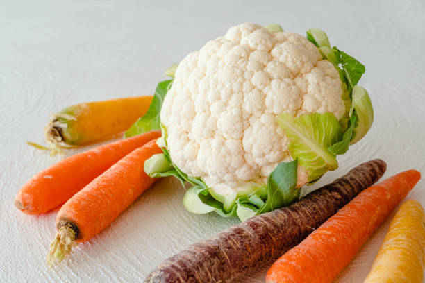 Carrots in many colors and cauliflower close up on white kitchen table