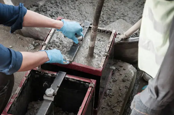 Pouring Concrete mix into mold and using concrete vibrator at construction site
