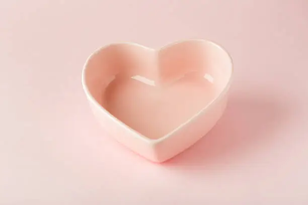 Photo of Empty pink plate in the shape of a heart on a pink background