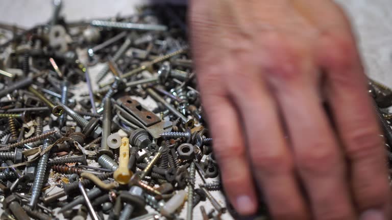 hand putting and sorting screws, nails, bolts and washers on the table. Selective focus, close up