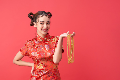 Attractive chinese asian female in tradition dress is holding gold necklace with joy and cheerful. Chinese happy new year. Wish concept.