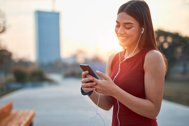 istock Modern young woman with cellphone making pause during jogging / exercise. 1304150009