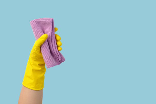 istock Hand in yellow glove with rag on blue background with copy space 1304152995