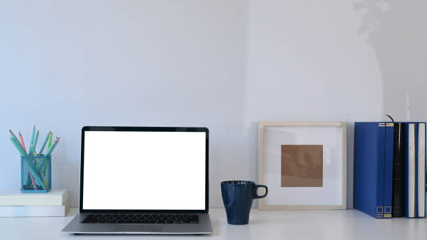 istock Simple workplace with laptop computer, books, coffee cup and pencils holder on white table. 1304153881