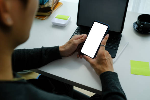 istock Close up view of man mobile phone with blank screen while sitting in front of computer tablet. 1304154768