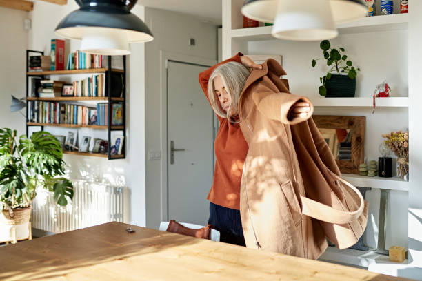 Senior Woman Putting on Coat Before Leaving Home