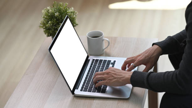 istock Young man using laptop computer on wooden table while sitting on floor in living room. 1304157627