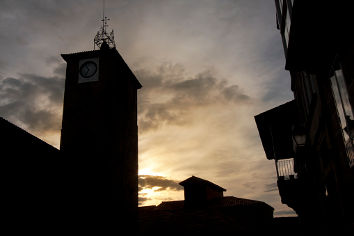 Ancient Santiago romanesque church ( XII century)  clock and bell tower, street view at dusk in Allariz old town, Ourense province, Galicia, Spain.
