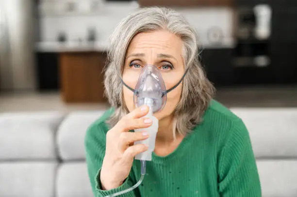 Photo of Elderly woman fells bad, holing a oxygen mask, lacking of oxygen