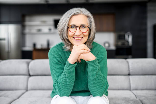 femme âgé sain s’asseyant sur le sofa - cheveux blancs photos et images de collection