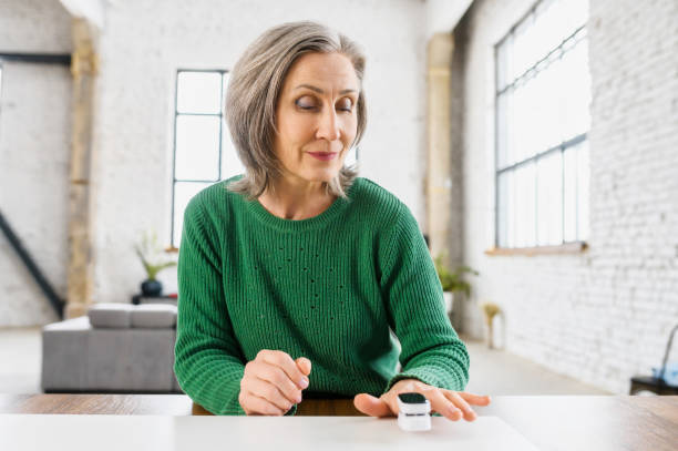 Aged healthy woman with pulse oximeter Aged healthy woman with wrinkles on the face, dressed in green warm sweater, determines the saturation of the lungs with oxygen, at home, loft style apartment, on the isolation,caring about her health pulse oxymeter stock pictures, royalty-free photos & images