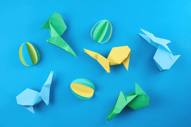 istock Paper origami Esater rabbits and colored eggs on blue background. Easter celebration concept 1304167017