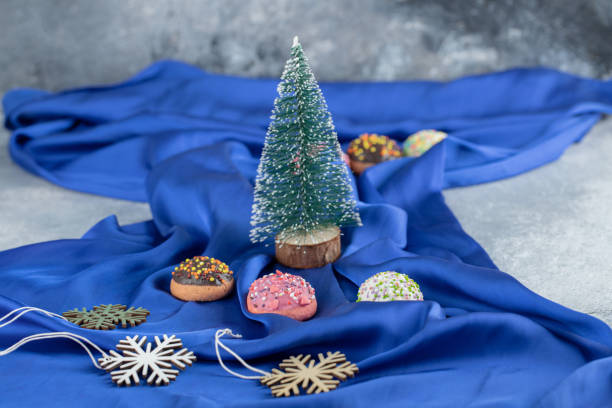 istock Colorful cookies with sprinkles and pine tree on blue cloth 1304168198