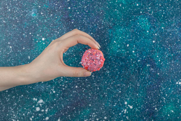 istock Female hand holding pink cookie with sprinkles 1304174647