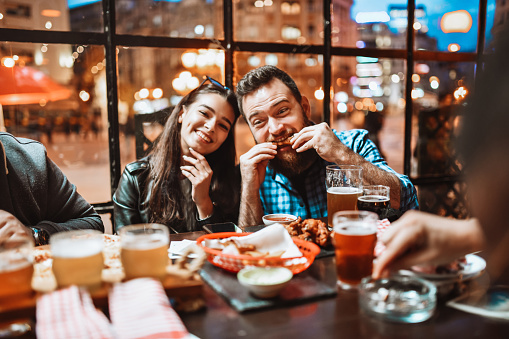 Cute Friends Enjoying Chicken Wings And Beer