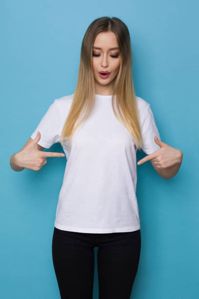 istock Young Woman Is Pointing At Her White Shirt Looking Down And Talking 1304178142
