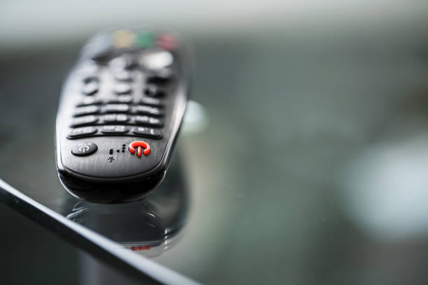 Black TV remote control with red button lying on glass table surface. Black TV remote control with red button lying on glass table surface. Home entertainment concept. remote control on table stock pictures, royalty-free photos & images