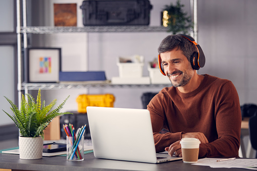 Marketing publicitario masculino o diseño creativo con auriculares inalámbricos en el escritorio trabajando en portátil photo